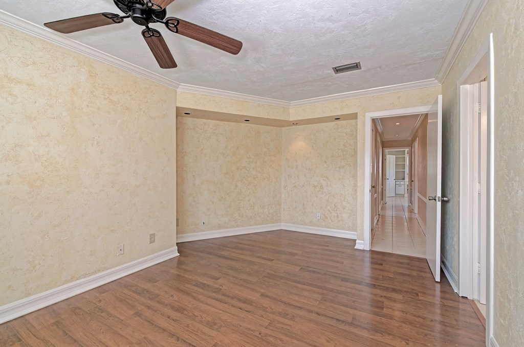 an empty living room with wood floors and a ceiling fan
