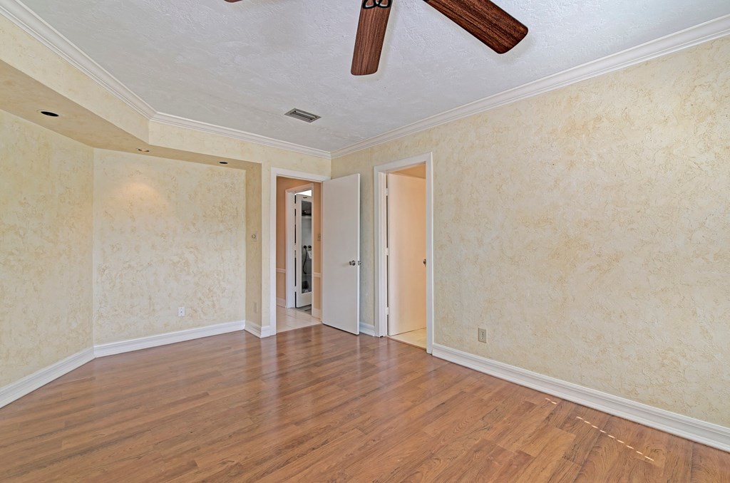 a empty living room with wood floors and a ceiling fan
