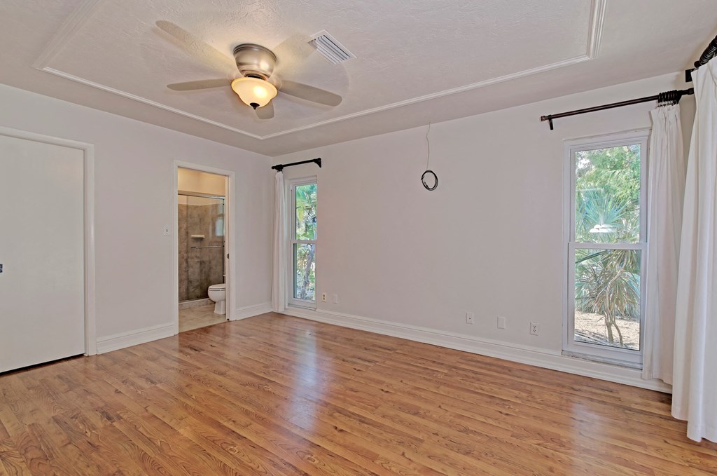 an empty living room with a ceiling fan and a window