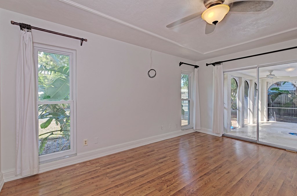 an empty living room with a ceiling fan and sliding glass doors