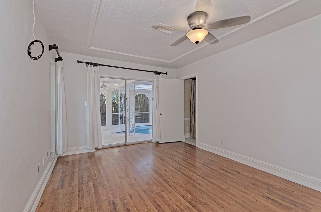 an empty living room with a ceiling fan and a door to a pool
