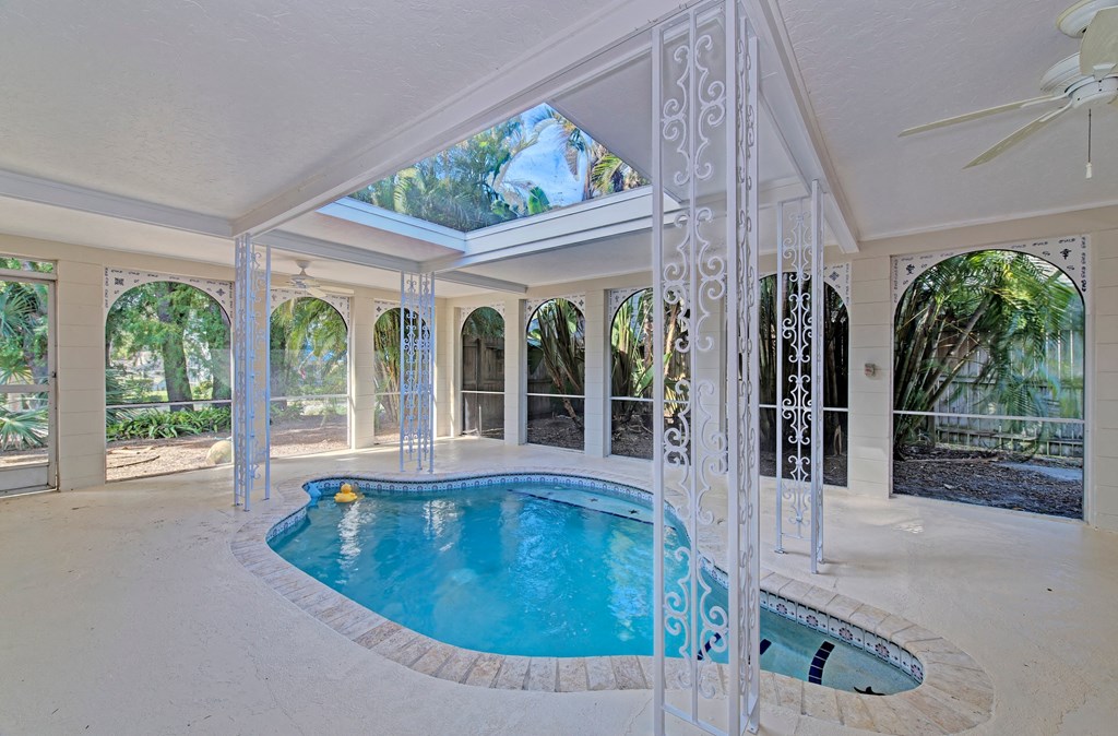 a pool and spa in a screened in pool room with a ceiling window