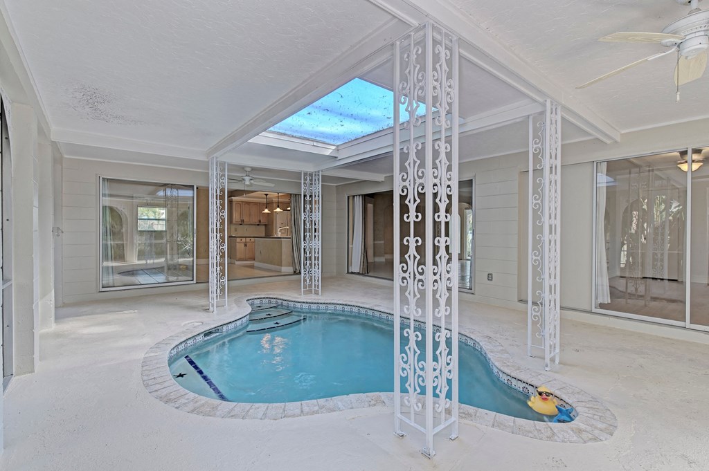 a pool and hot tub in a large room with a ceiling window