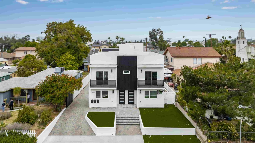 an aerial view of a white house with a black roof and green grass