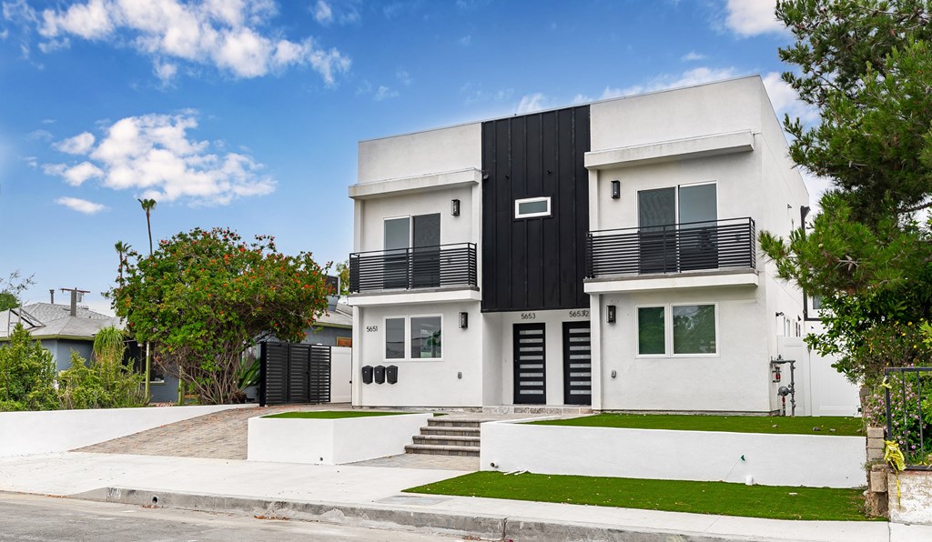 the exterior of a house with a white and black facade and a sidewalk