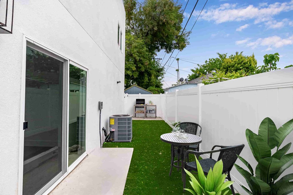 a backyard with a table and chairs and a grill