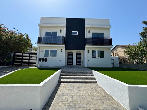 the front of a house with a lawn and a walkway