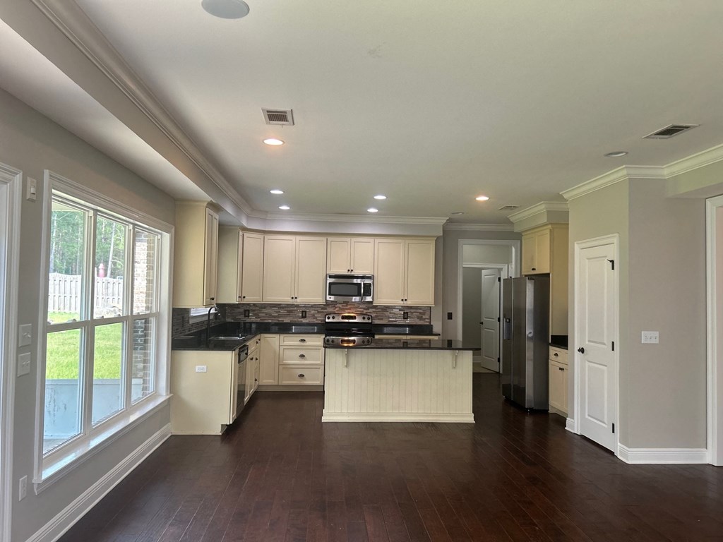a kitchen with white cabinets and black counter tops and a large window