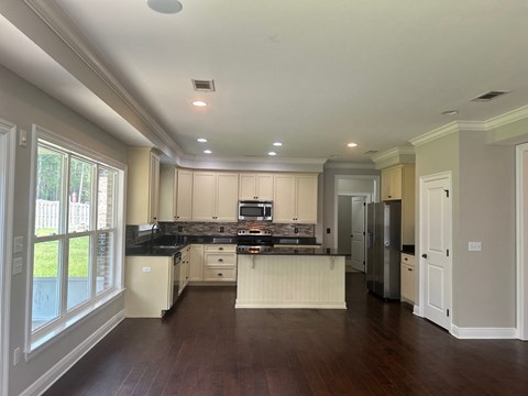 a kitchen with white cabinets and black counter tops and a large window