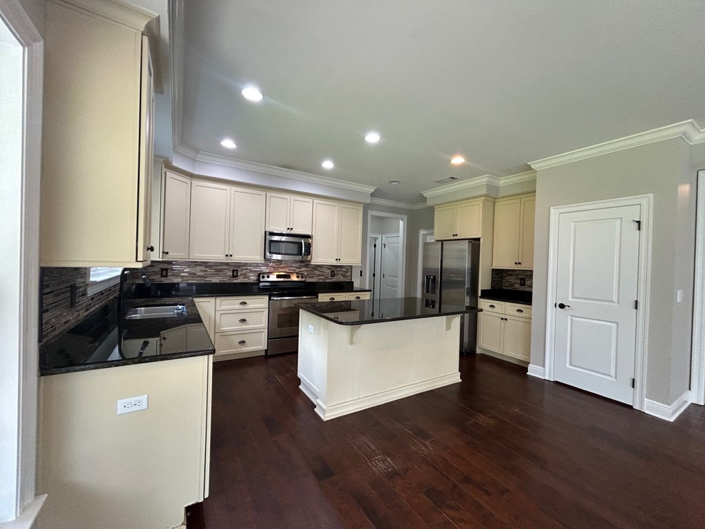 a large kitchen with white cabinets and black counter tops
