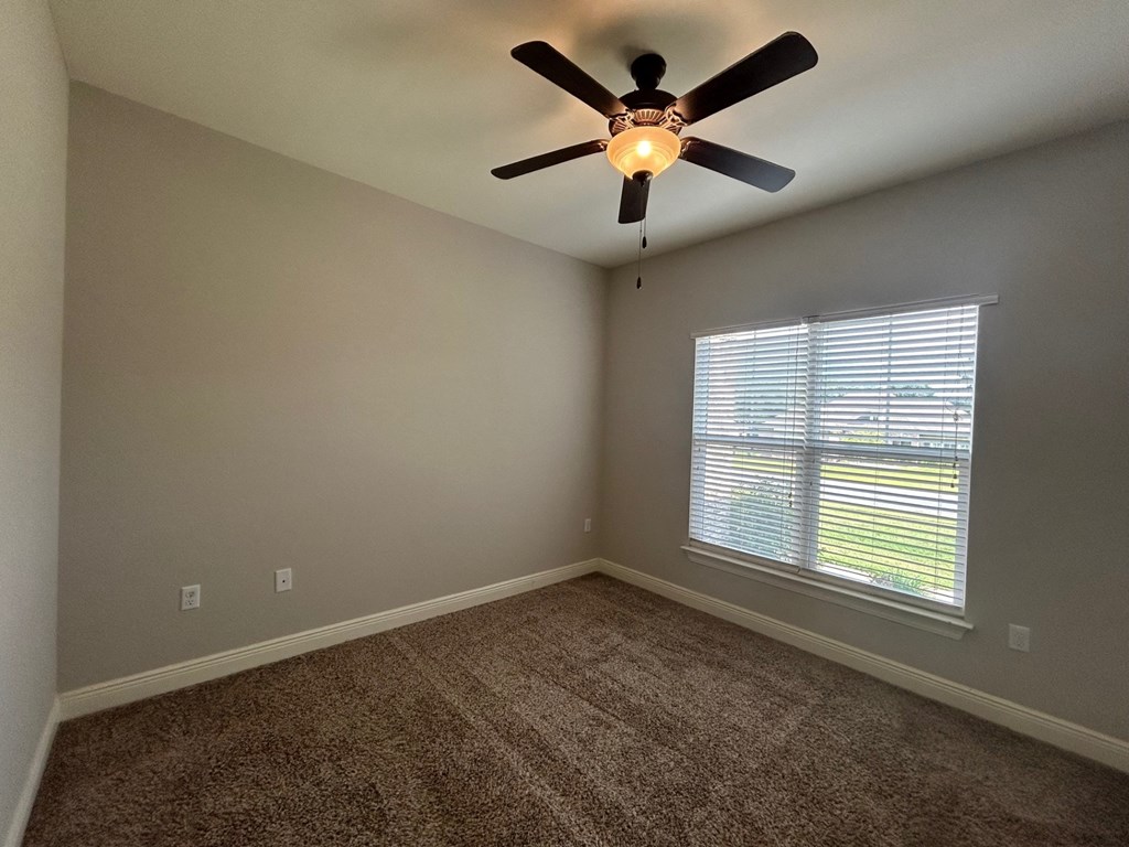 an empty bedroom with a ceiling fan and a window