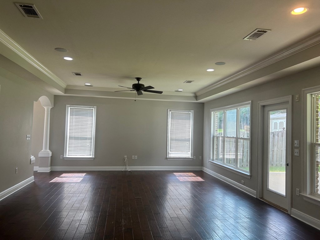 an empty living room with a ceiling fan and windows