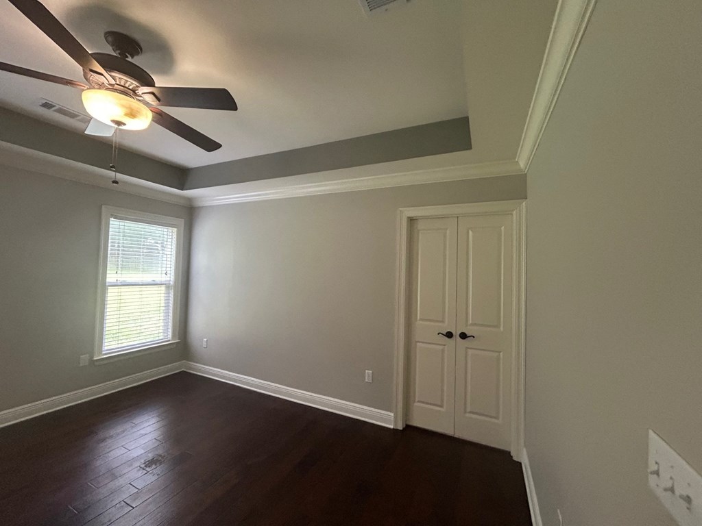 an empty living room with a ceiling fan and a door