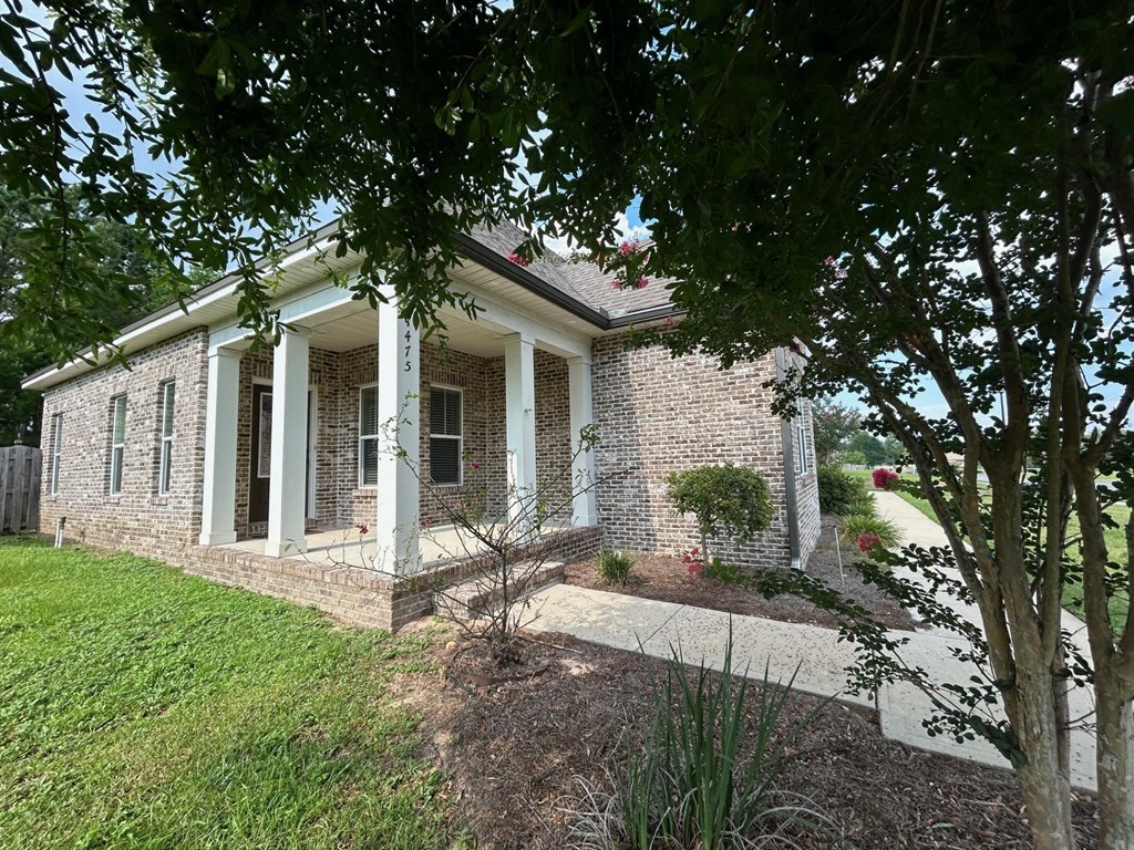 a brick house with white pillars and a sidewalk