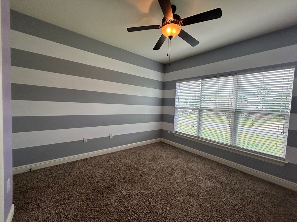 the bedroom of a home with striped walls and a ceiling fan
