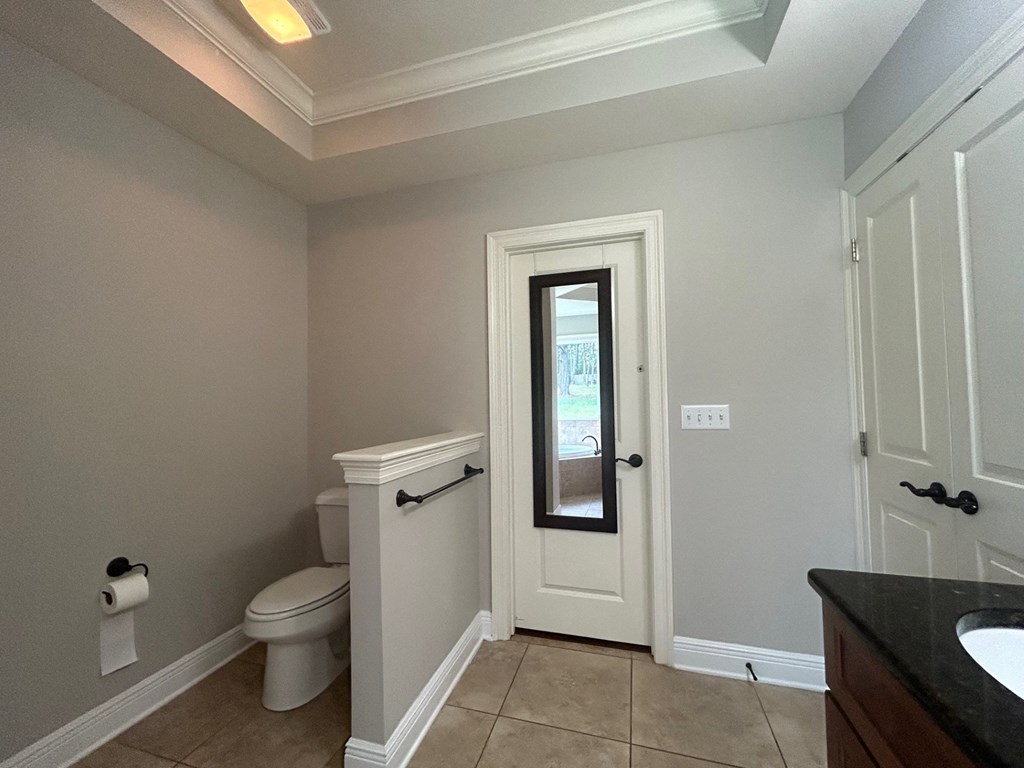 a bathroom with a toilet and a door to a closet
