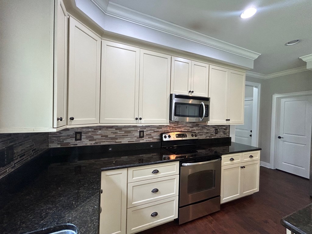 a kitchen with white cabinets and a black counter top