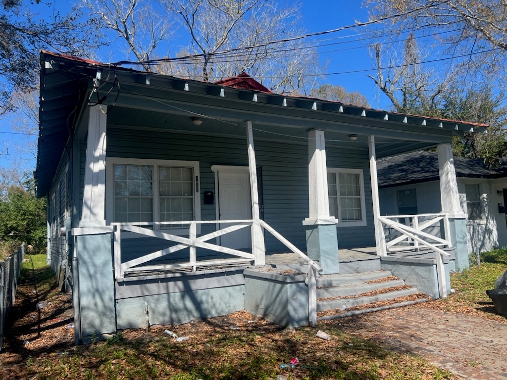 A blue house with white railings and a red roof.