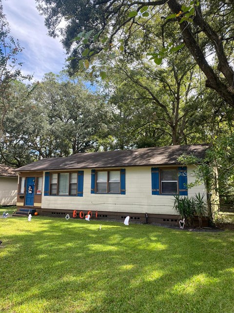 a small white house with blue doors and windows on a lawn