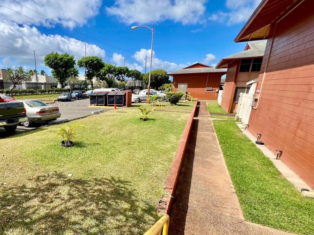 a yard in front of a building with cars parked in a parking lot
