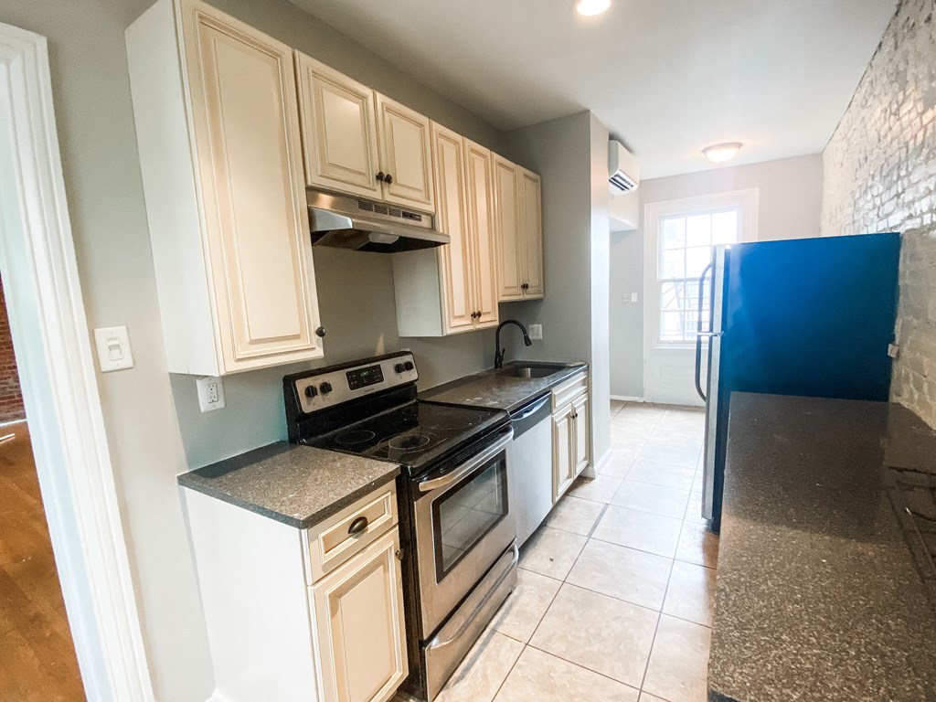 an empty kitchen with white cabinets and a blue refrigerator