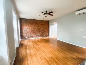 an empty living room with a brick wall and wooden floors