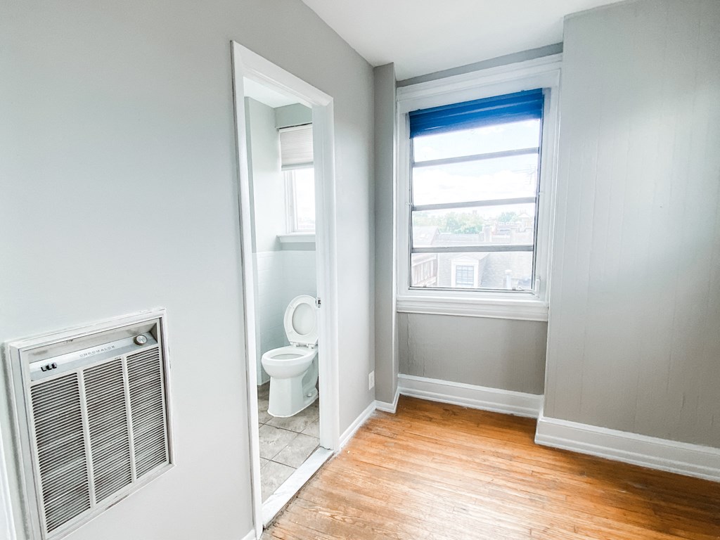 an empty room with a toilet and a window and a door to a bathroom