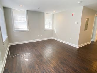 an empty living room with wooden floors and white walls