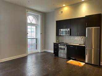 an empty kitchen with stainless steel appliances and black cabinets