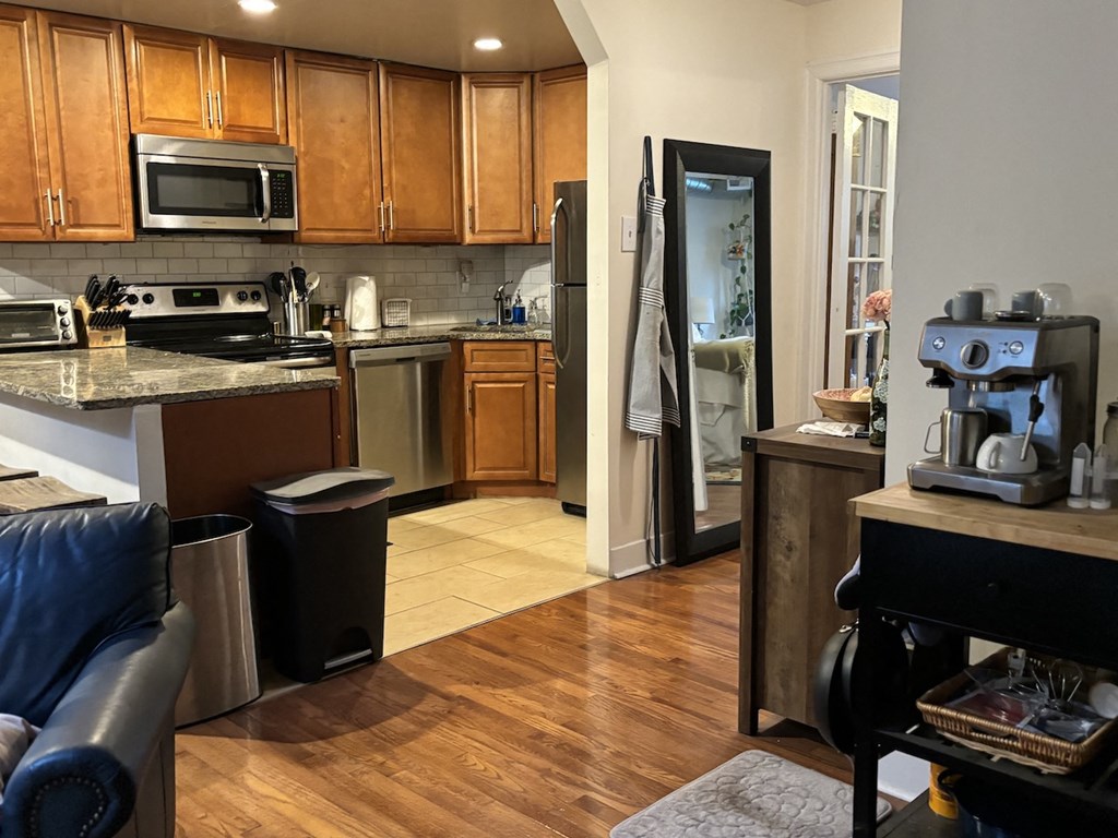 the kitchen and living room of a home with wood floors and stainless steel appliances