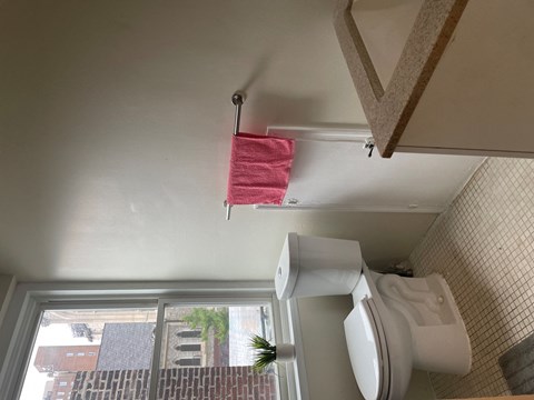 a bathroom with a toilet and a window and a red towel