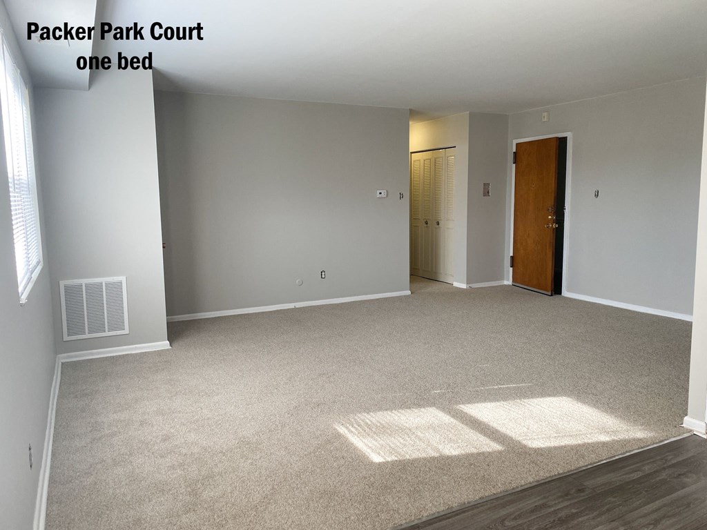 an empty living room with carpet and a door to the bathroom