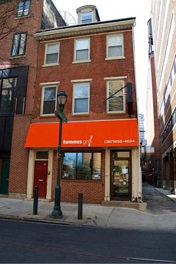 a brick building with an orange awning on a street corner