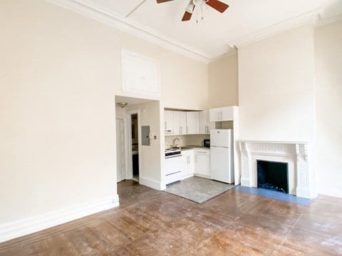 an empty living room with a kitchen and a fireplace