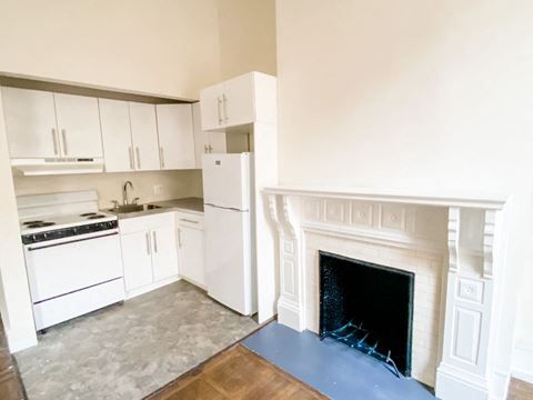 an empty kitchen with a fireplace and white appliances
