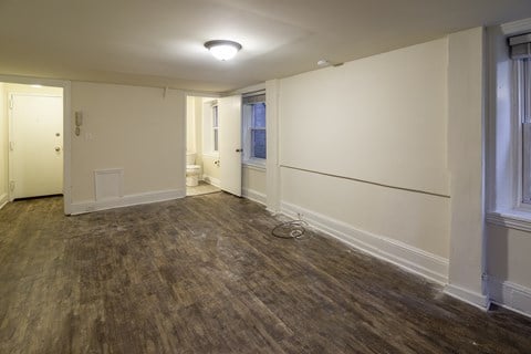 an empty living room with white walls and a wooden floor