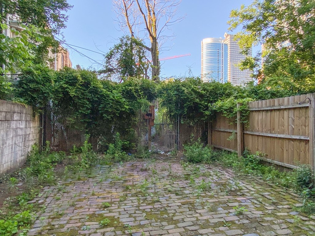 a backyard with a wooden fence and a brick road