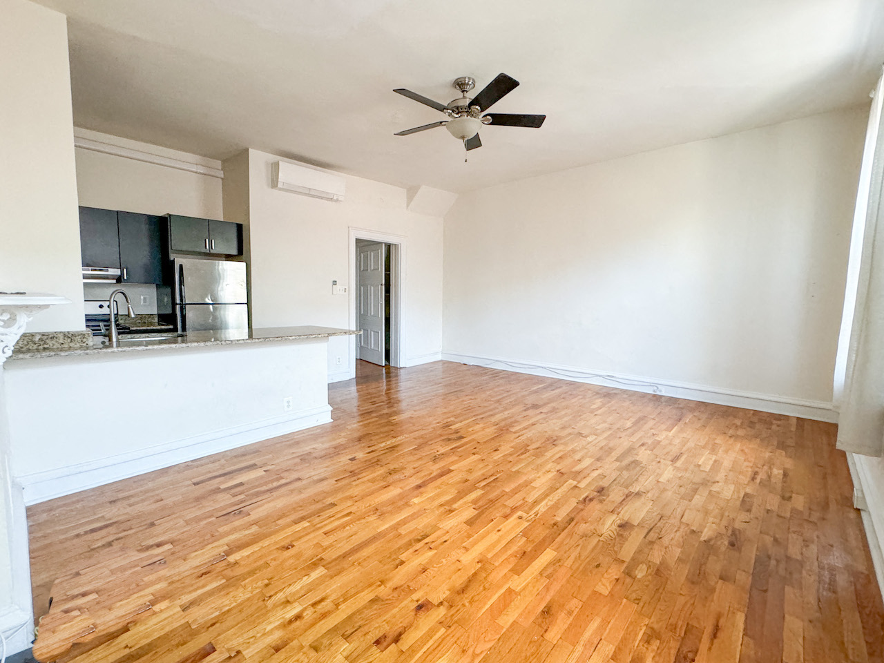 an empty living room with wood floors and a ceiling fan