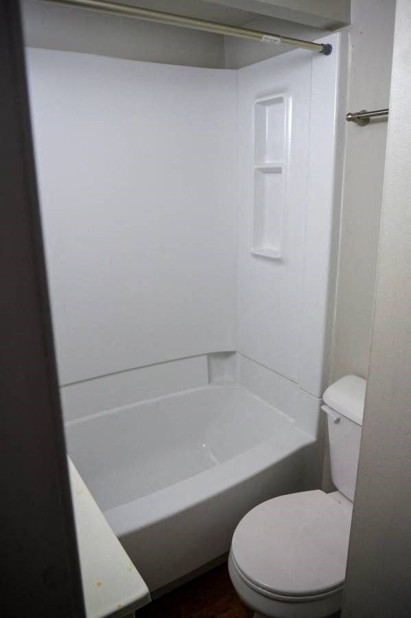a white bathroom with a toilet and a tub