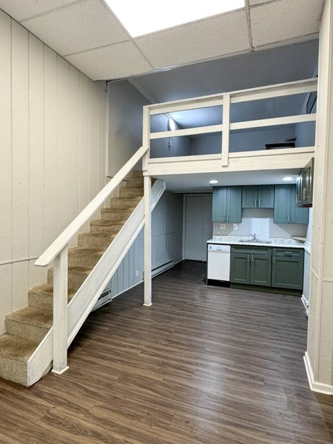 a room with a staircase and a kitchen and a loft