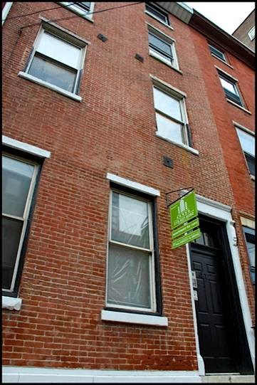 a brick building with a green sign in front of it