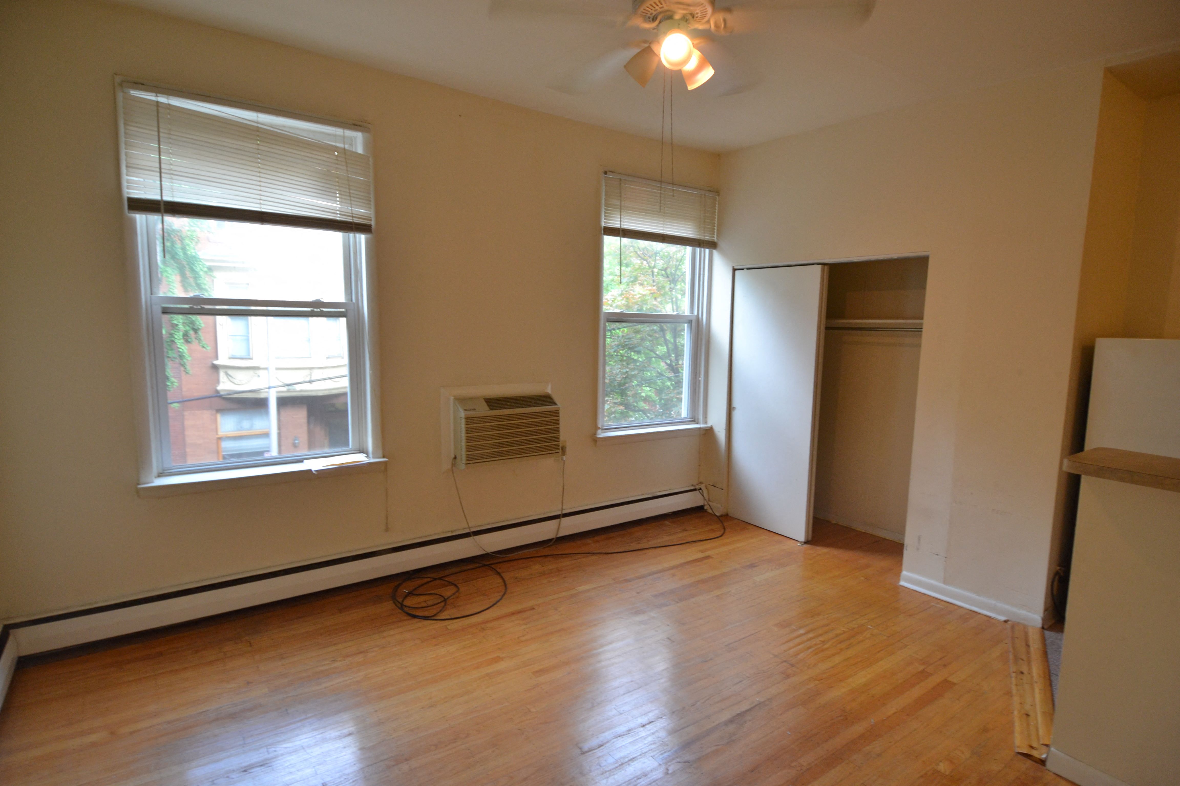an empty living room with wood floors and two windows