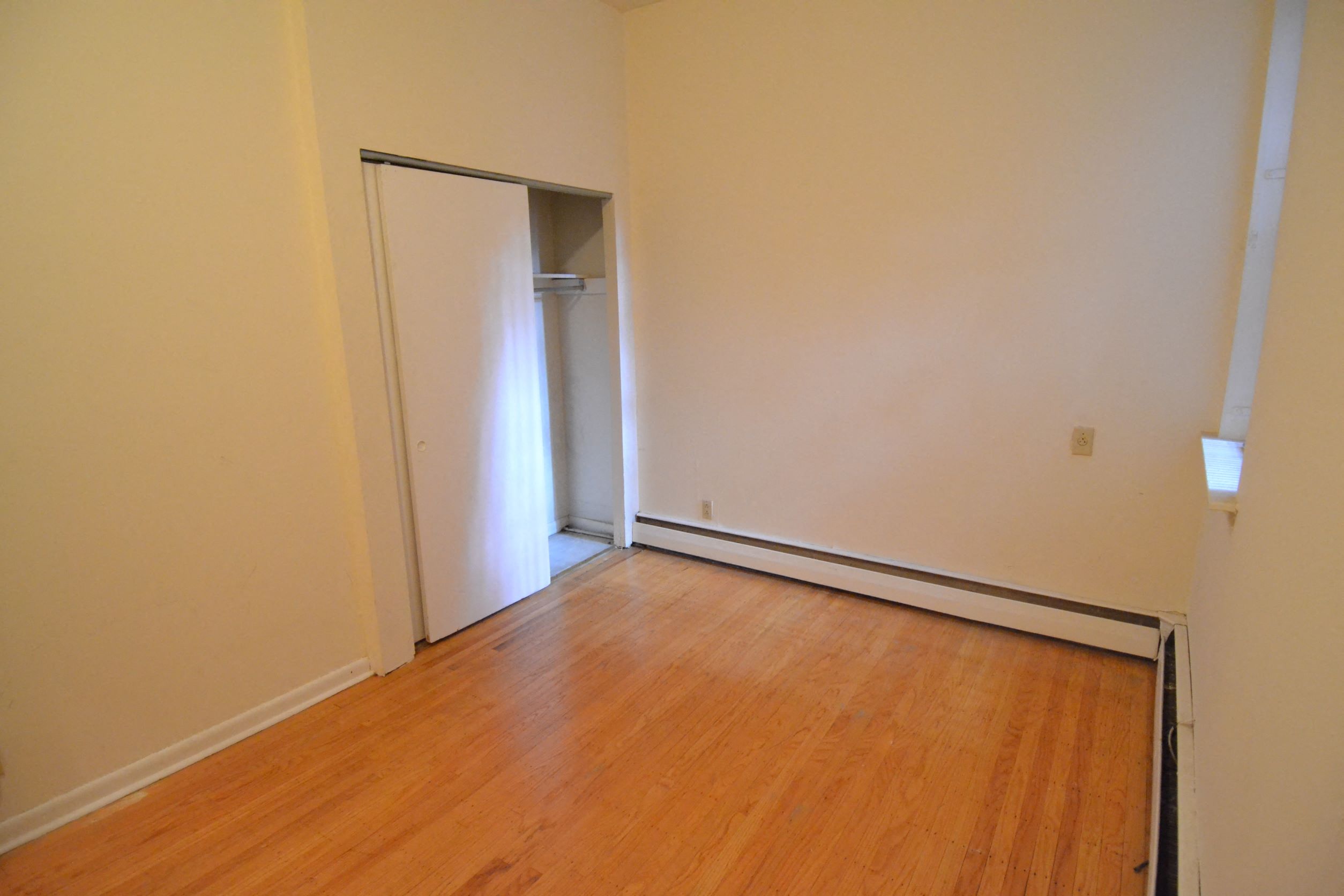 a bedroom with a door to a closet and a wooden floor