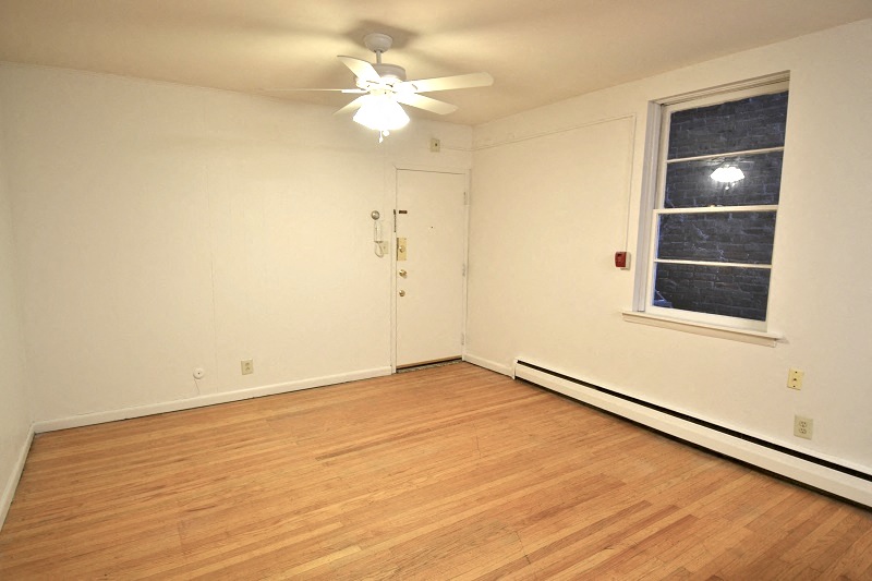 an empty bedroom with a ceiling fan and a window