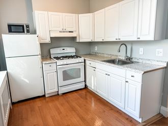 a kitchen with white cabinets and appliances and a wooden floor