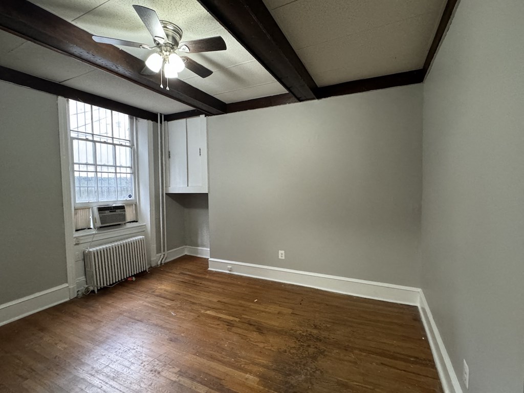 an empty living room with wood floors and a ceiling fan