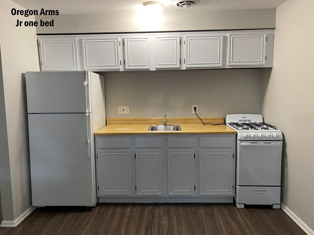 an empty kitchen with white cabinets and a stove and refrigerator