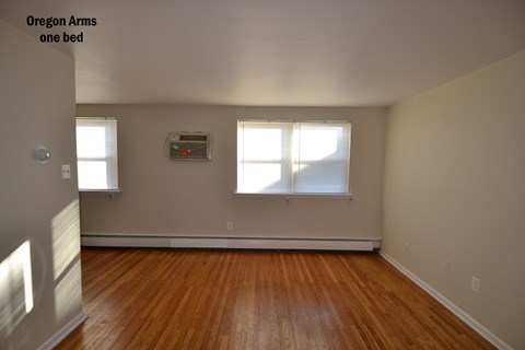 an empty room with wooden floors and two windows