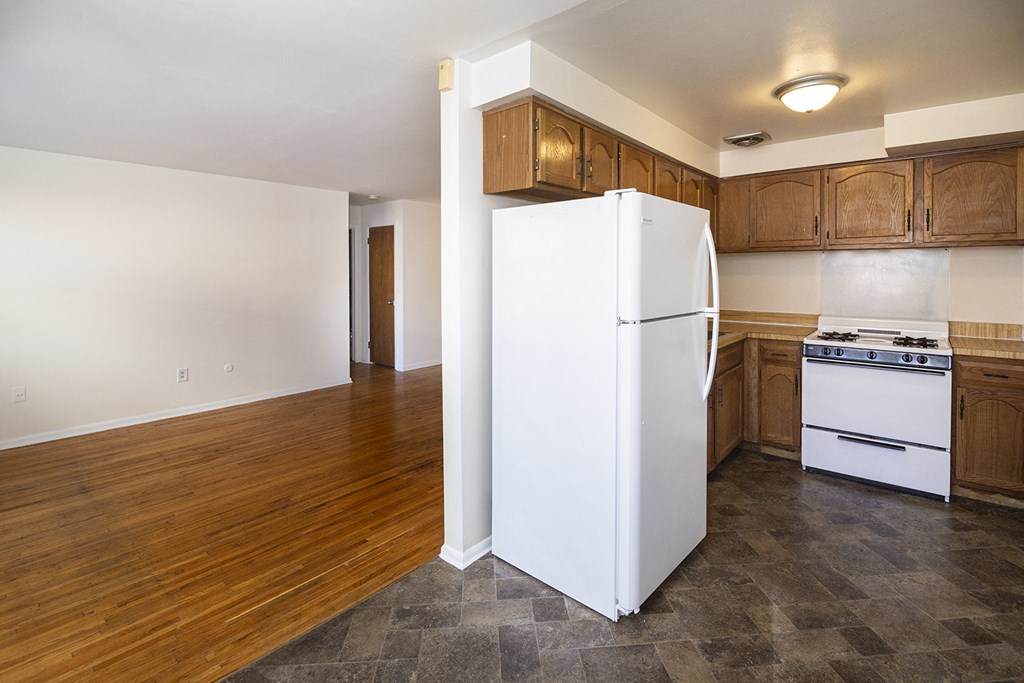 an empty kitchen with a white refrigerator and stove