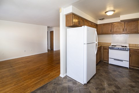 an empty kitchen with a white refrigerator and stove